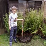 A boy in Bristol plants one of the 12,000 fruit trees that we're giving to children to plant in their home gardens.